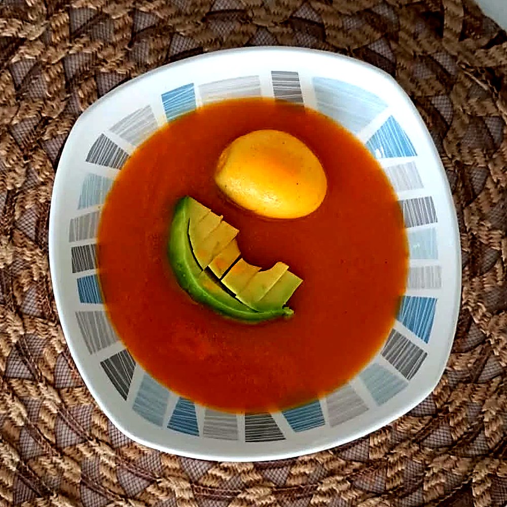 Plato de sopa de tomate con huevo y aguacate